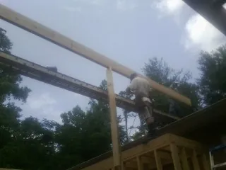 Carpenter setting a ridge beam over a new addition frame — Ice Dam Removal by Roofing Brothers in Penfield
