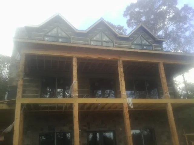 Dormers and porch framing on a large log home under construction — Roof Coating work by our crew in Penfield