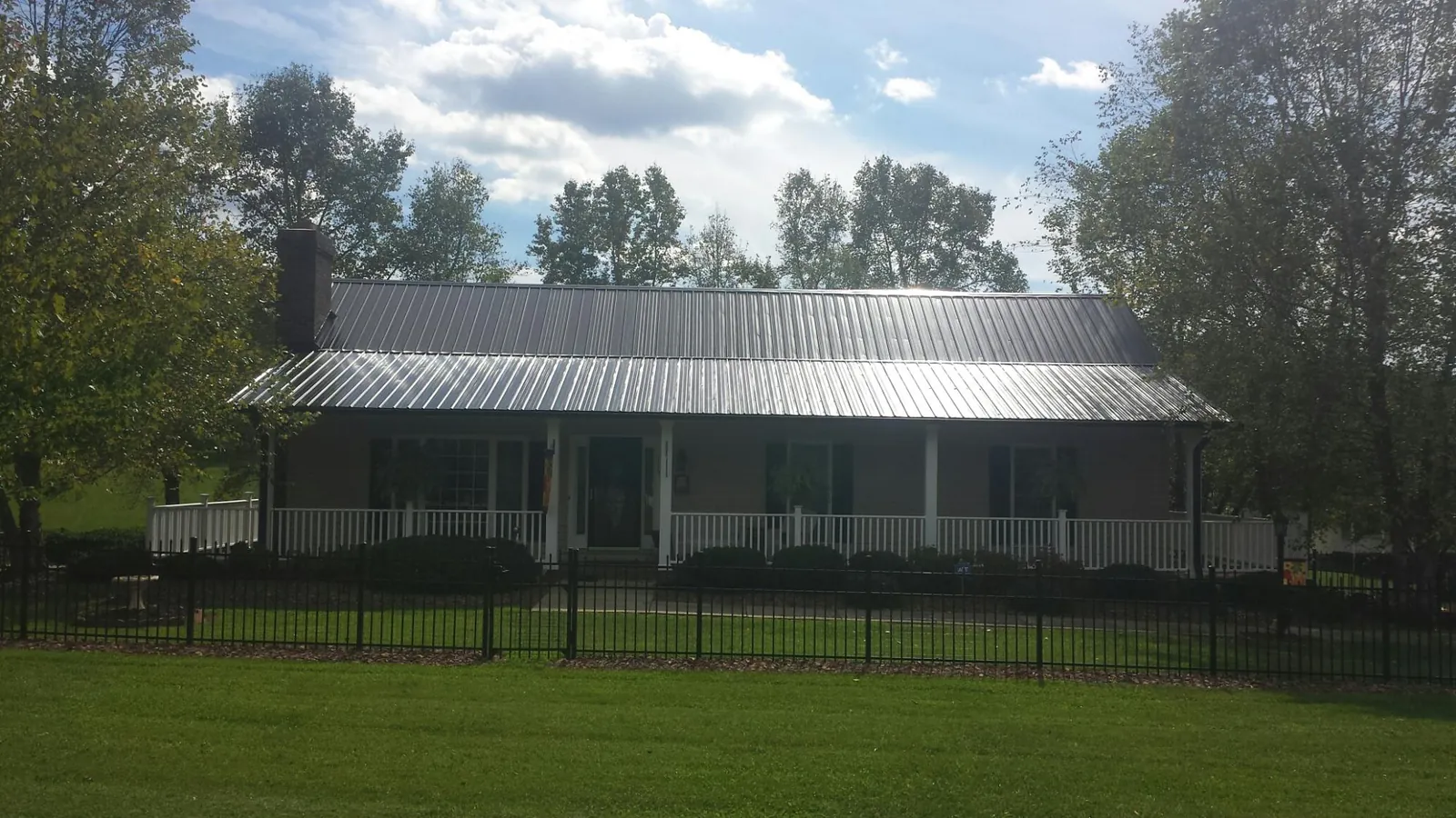 Gray metal roof on a brick ranch with a full width front porch — Gutter Guard Installation work by our crew in Penfield